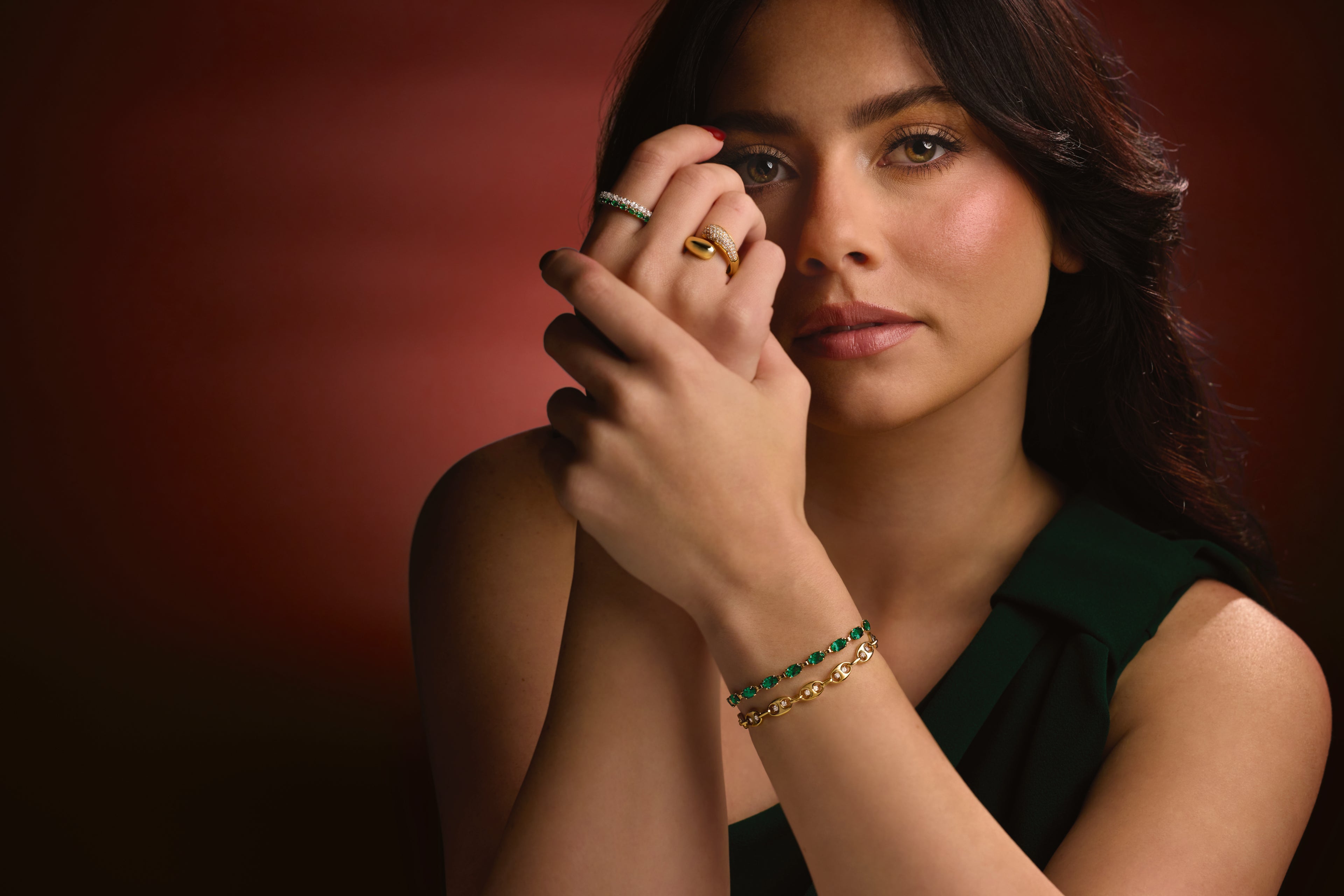 Woman wearing gold rings and a green gemstone bracelet