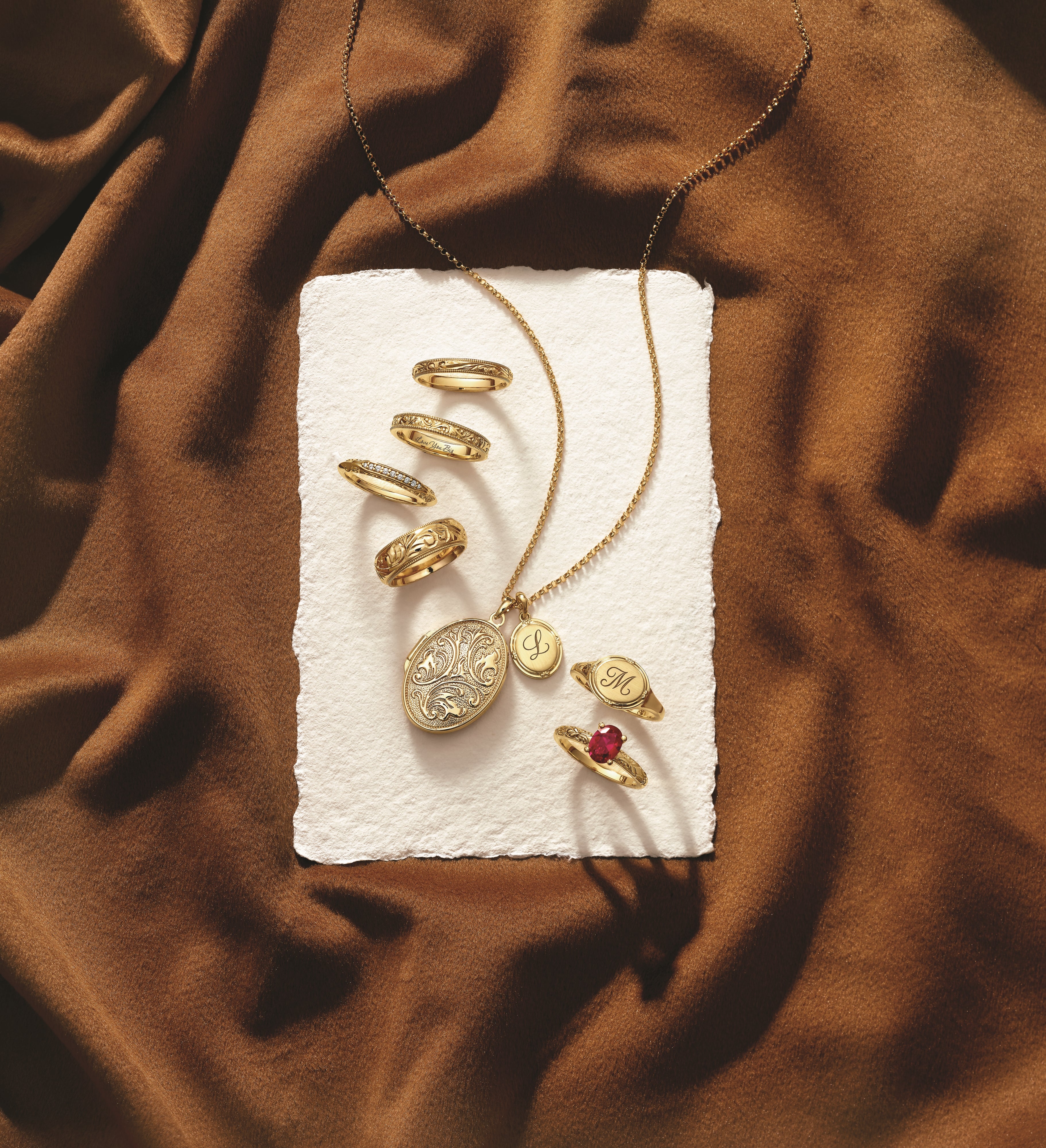 Vintage gold lockets, rings and necklaces displayed on brown fabric