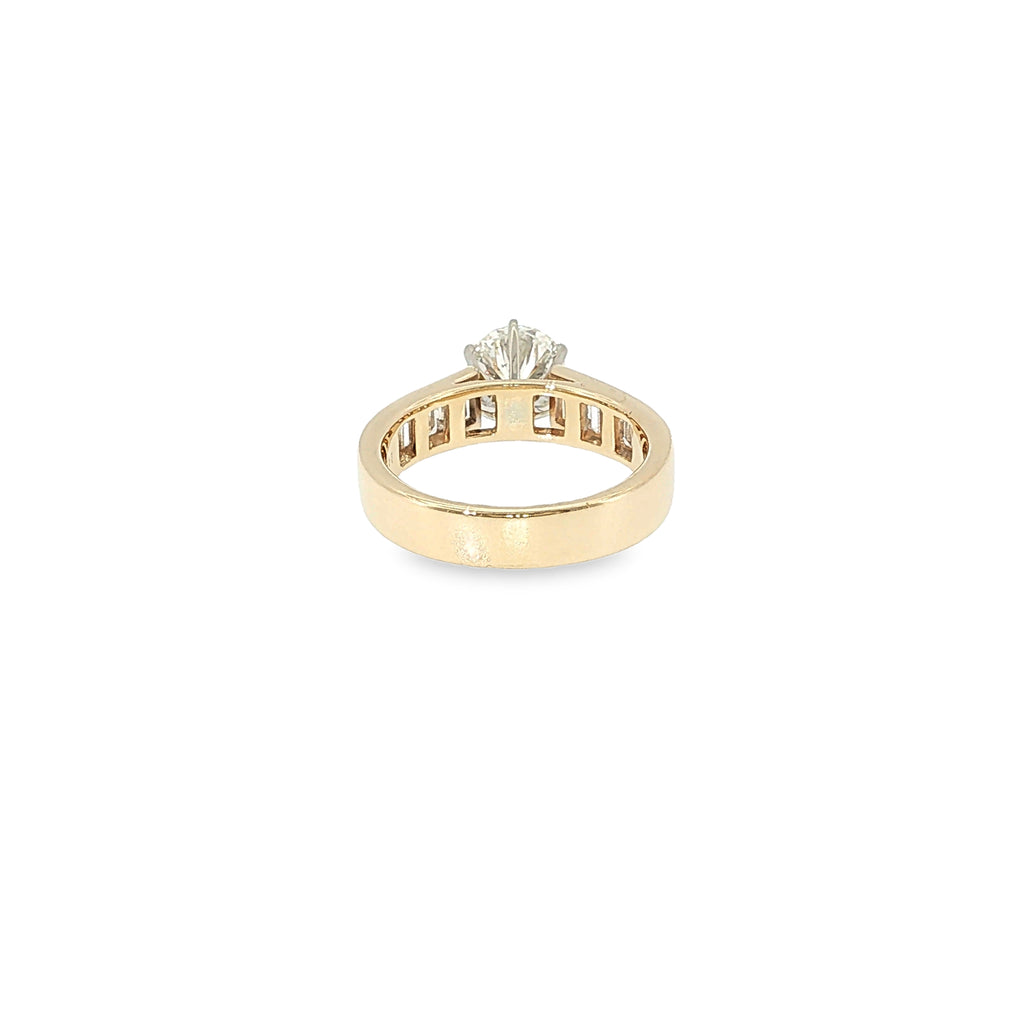 14K yellow gold engagement ring with a round brilliant diamond center and channel-set baguette diamond accents.