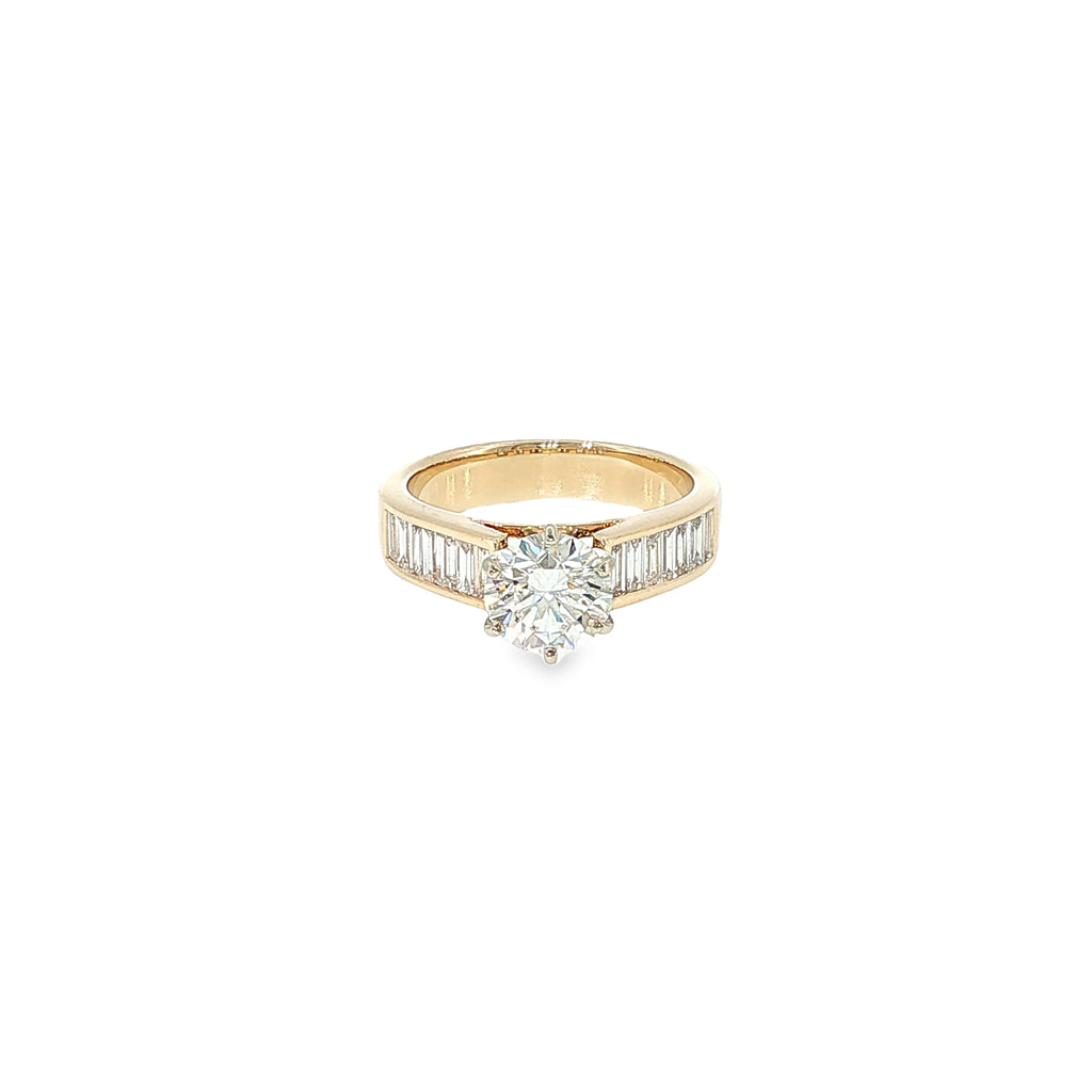 14K yellow gold engagement ring with a round brilliant diamond center and channel-set baguette diamond accents.