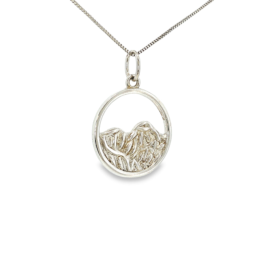 Sterling silver round pendant with an openwork mountain landscape and textured mountain peak design.