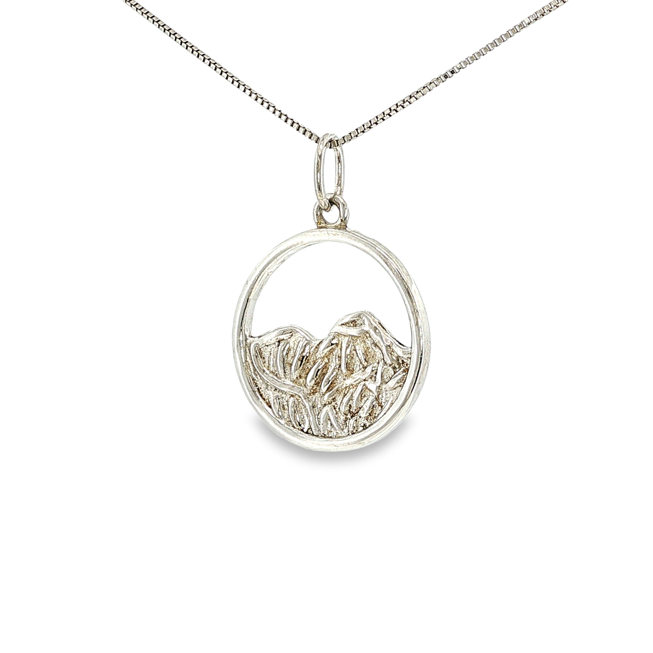 Sterling silver round pendant with an openwork mountain landscape and textured mountain peak design.