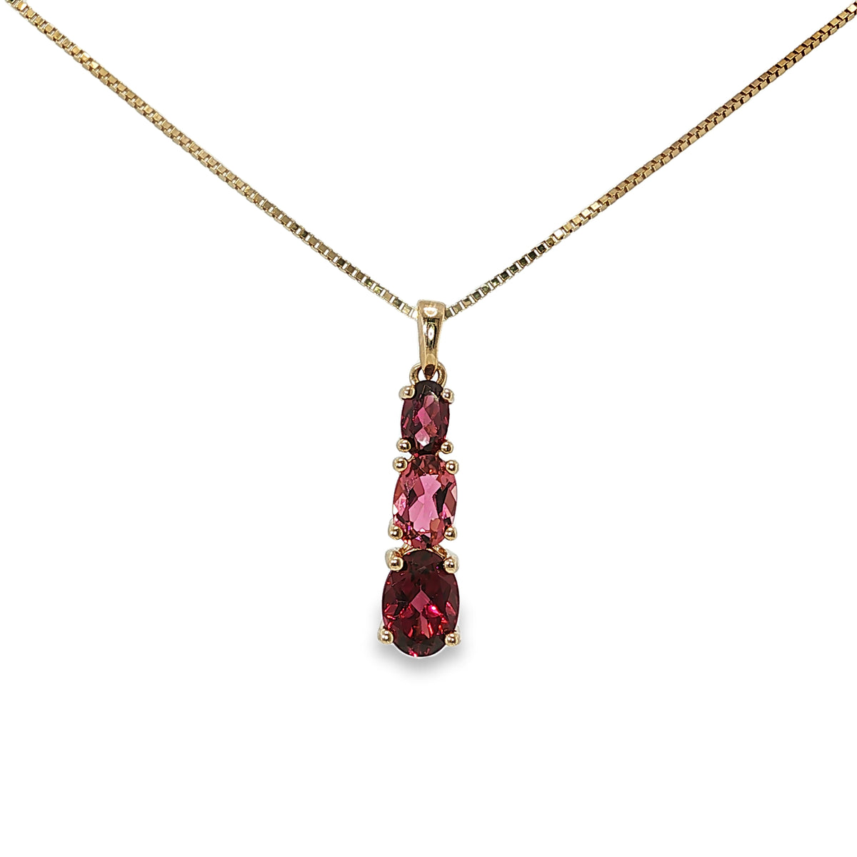 14K yellow gold three-stone pendant with two garnets and one pink tourmaline in a vertical drop design.