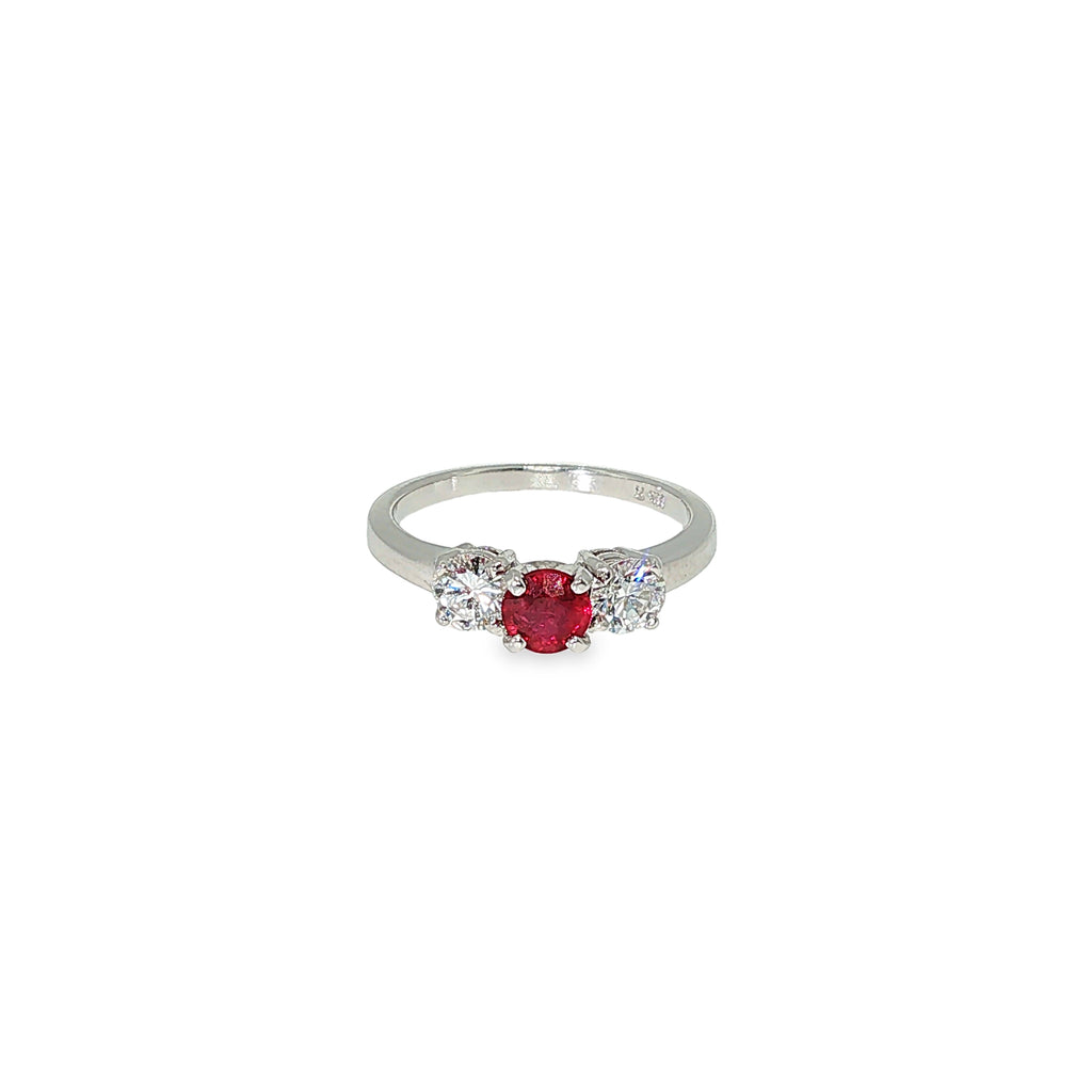 Three-stone ruby and diamond ring with a round red ruby center and two round brilliant diamond side stones in 14K white gold.
