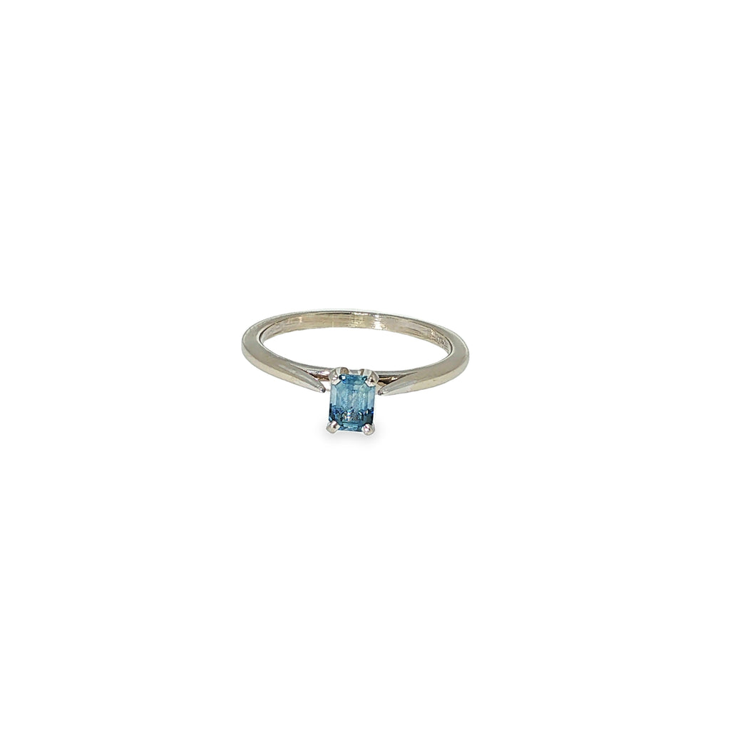 14K white gold solitaire ring with a light blue emerald-cut sapphire in a four-prong setting.