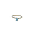 14K white gold solitaire ring with a light blue emerald-cut sapphire in a four-prong setting.