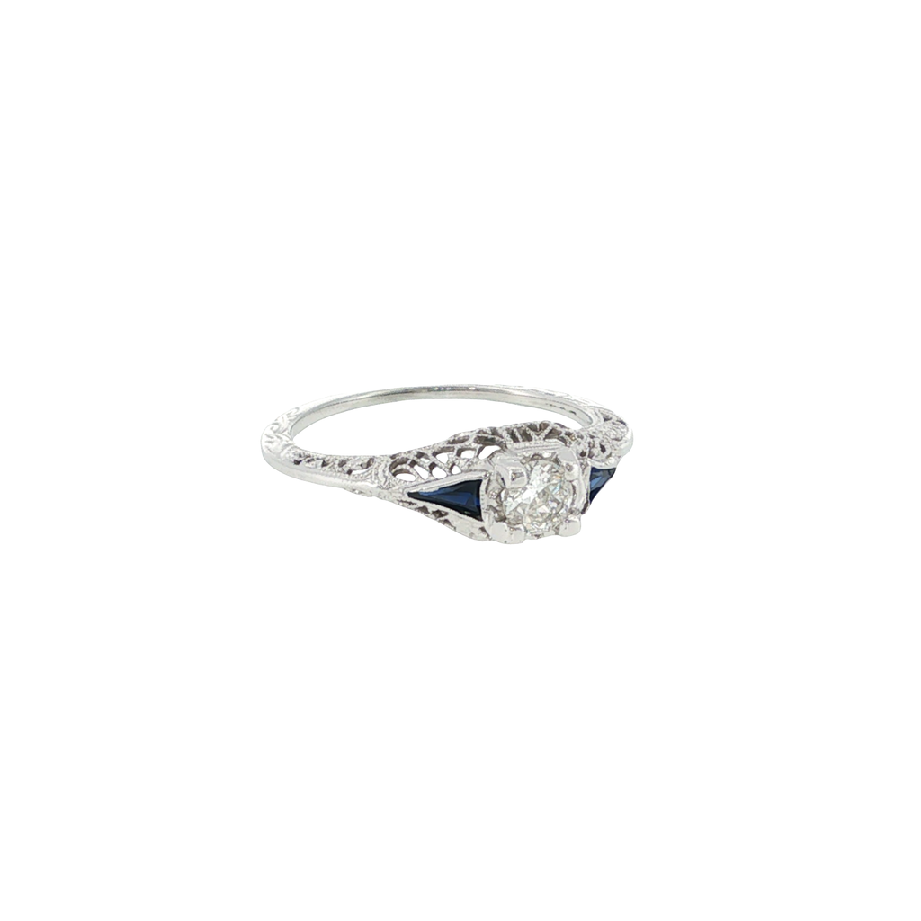 18K white gold vintage-style ring with an Old European cut diamond center and deep blue synthetic sapphire accents.