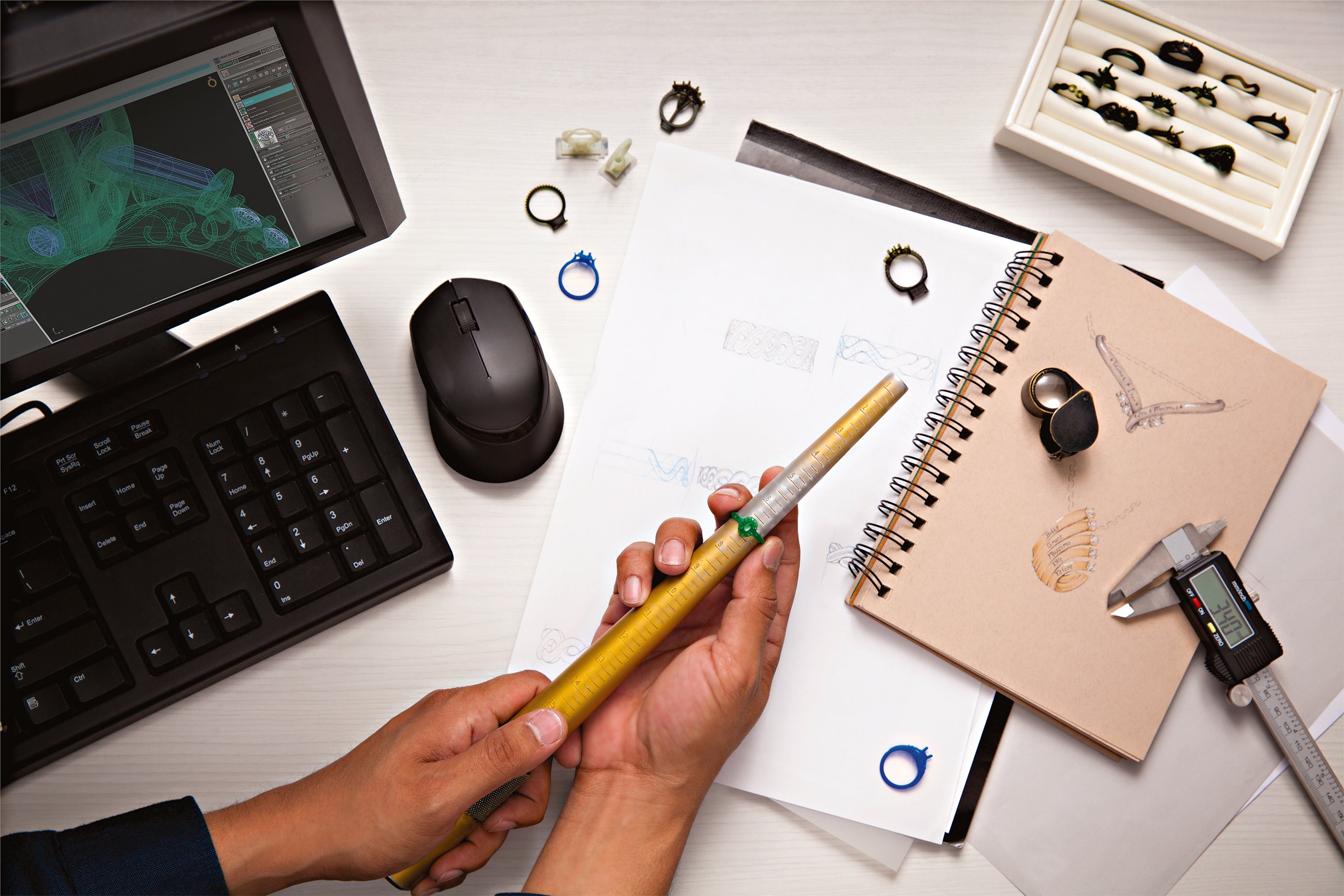 Person holding a stylus over a digital tablet with a design on a desk.