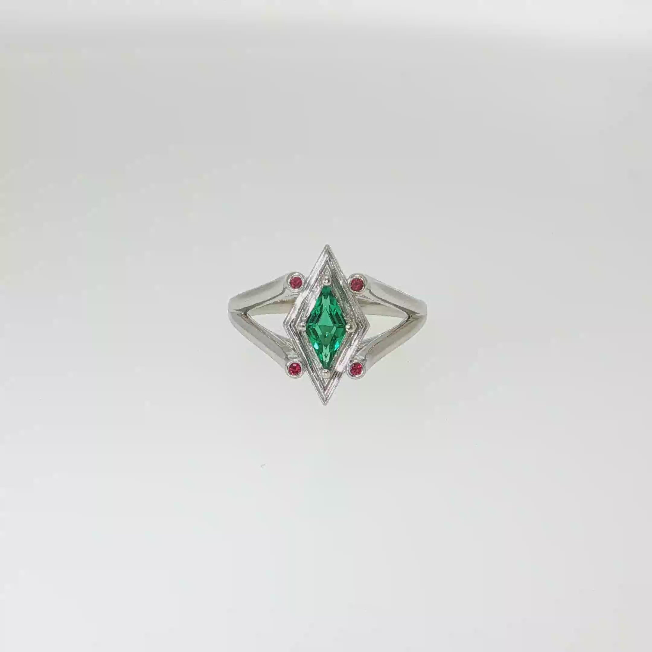 14K white gold geometric ring with a diamond-shaped lab-grown emerald and four small ruby accents.