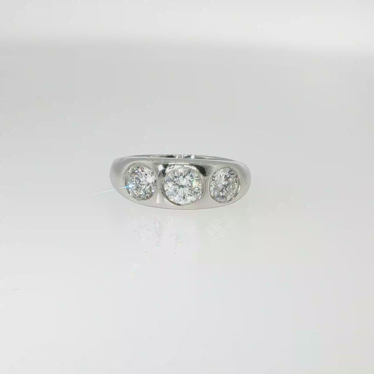 Platinum band with three round brilliant diamonds flush set across the center.