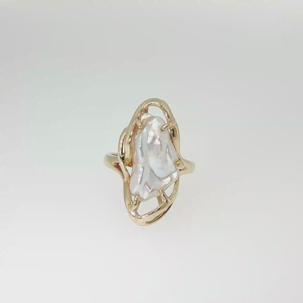 14K yellow gold freeform ring with an elongated freshwater baroque pearl in a sculptural openwork setting.