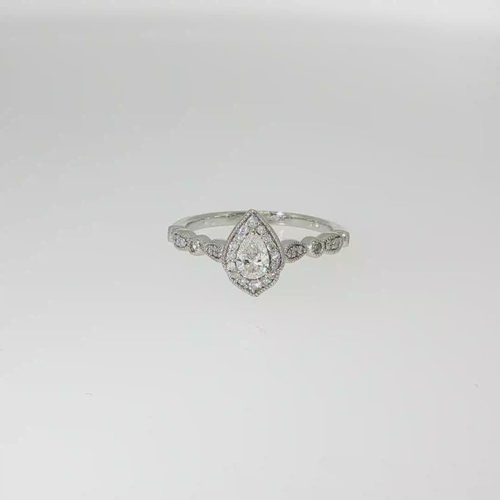 Pear-shaped diamond halo engagement ring in 14K white gold with round diamond accents along the band.